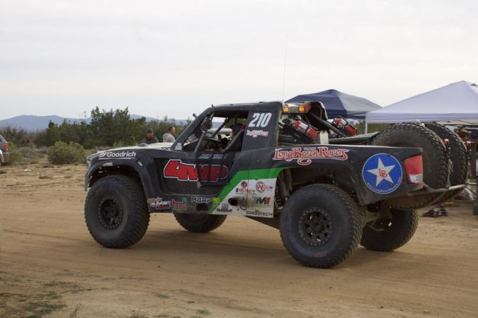 Black off-road racing truck numbered 210, featuring Long Beach Racers and 4WP branding, driving on a dirt track.