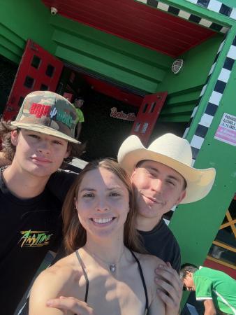 Three people pose for a selfie in front of a green building entrance.