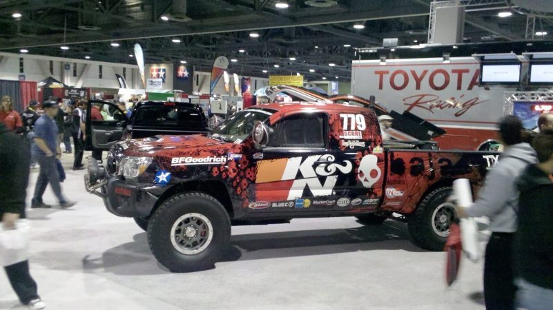 A K&N branded off-road racing truck with a red and black skull pattern on display at a trade show.