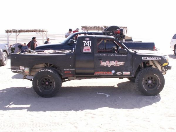 Black off-road racing truck with number 741 parked in a desert area.
